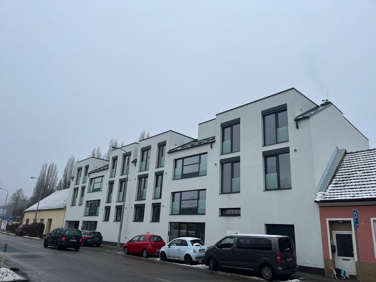 Řada bytových domů s dokončenou fasádou při pohledu z ulice