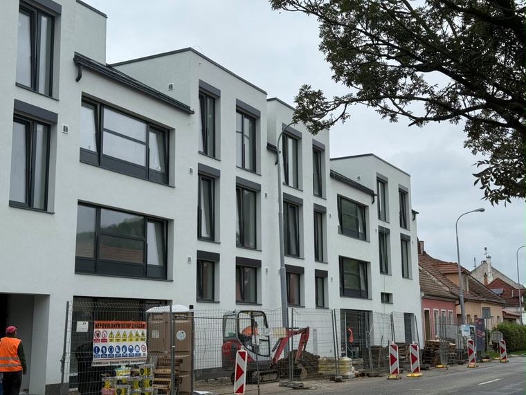 Bytový dům s moderní bílou fasádou a velkými okny