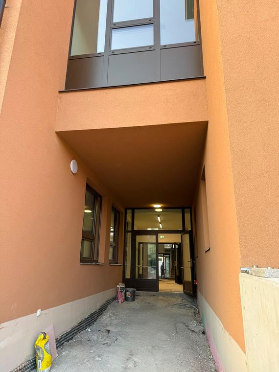 Vstup do bytového domu s dokončenou fasádou a zádveřím