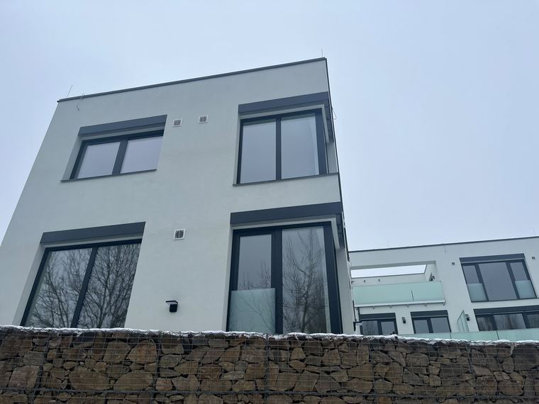 Rodinný dům s bílou fasádou a kamennou podezdívkou